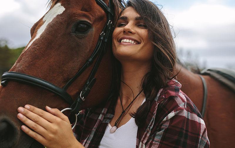 smiling woman hugs horse